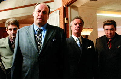 Four men in formal suits standing in a room, looking forward with serious expressions.