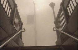 Low angle view looking up concrete stairs toward a foggy sky between two railings.