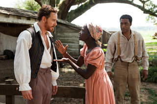 A man in a vest and a woman in a pink dress gesture emphatically while talking outdoors.