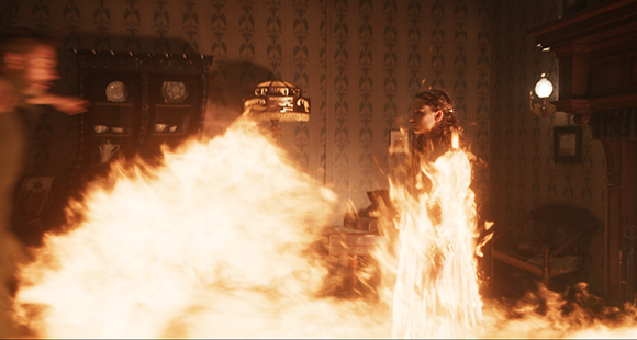 A person stands in a patterned room, partially covered by large, bright orange flames.