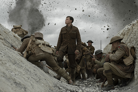 Soldiers in a dirt trench look upward as debris and smoke from an explosion fill the sky.