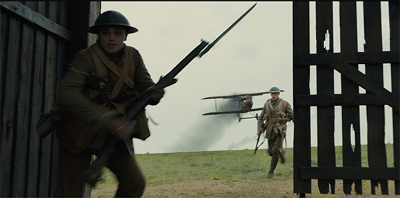 Two soldiers in vintage military uniforms run through a wooden gate toward a grassy field with a biplane.