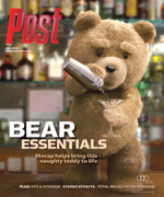 A teddy bear with a cocktail shaker mixes a drink in a glass, standing behind a bar with bottles.