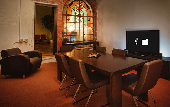 A dark wood conference table with six chairs, a television, and a large arched stained glass window.