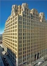 A large, tan multi-story skyscraper with many windows and stepped architectural details.