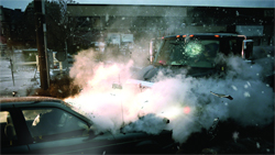 A dark vehicle surrounded by large clouds of white smoke or steam in a snowy outdoor area.