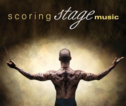 A shirtless man with tribal tattoos on his back and arms stands with arms outstretched.