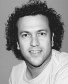 Black and white headshot of a man with dark curly hair looking toward the camera.