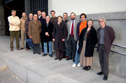 A group of thirteen people standing in a row on outdoor stone steps.