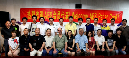 A large group of men and women posing together in front of a red banner with yellow text.