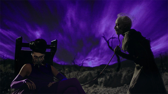 A person in a chair wears a mask while another person holds a tube connected to them under a purple sky.