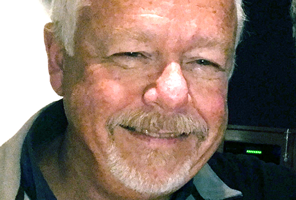 Close-up of a smiling man with white hair, a mustache, and a goatee.