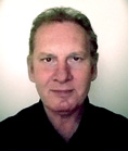 A man with light skin and short, light brown hair looking directly at the camera against a white background.