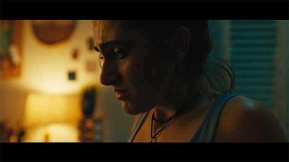 Profile view of a woman with a worried expression in dim, warm lighting.