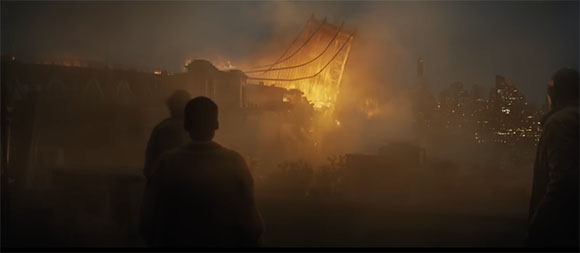 Silhouettes of people watching a large bridge on fire amidst thick smoke at night.