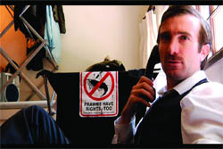 A man talking on a phone next to a sign reading 'Prawns Have Rights Too' with a prawn icon.