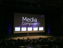 A large projection screen displays the text 'Media Composer' in a dark theater filled with an audience.