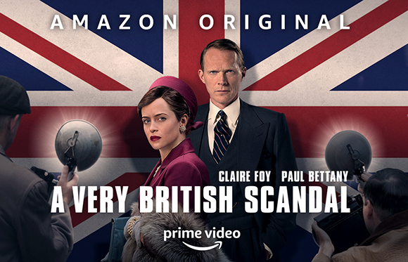 Claire Foy and Paul Bettany stand before a Union Jack flag with paparazzi cameras in the foreground.