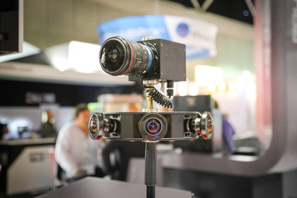 A specialized camera device with one top lens and three bottom lenses mounted on a black stand.