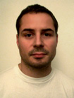 A man with short dark hair and light facial hair looking directly at the camera.