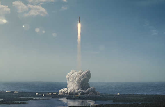 A rocket ascends vertically, leaving a long trail of fire and a large cloud of white smoke at the launch site.