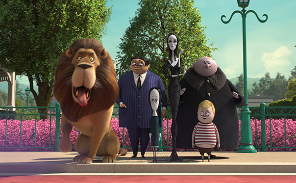 A group of animated characters, including a large lion and several people, posing in front of green trees.