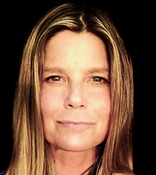 A close-up portrait of a woman with straight blonde hair looking directly at the camera against a black background.