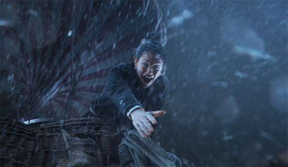 A man with dark hair reaches his hand forward amidst heavy rain and dark shadows.