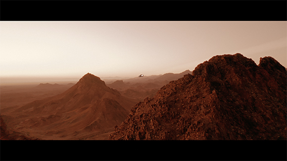 A wide view of rugged, reddish-brown mountains under a pale, dusty sky.
