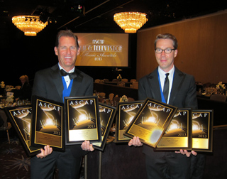 Two men in tuxedos smiling and holding multiple gold ASCAP award plaques at an awards ceremony.