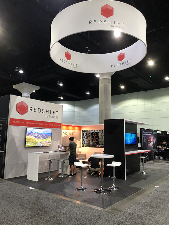 Trade show booth for Redshift by Maxon, featuring a large overhead circular sign and multiple displays. People are interactin
