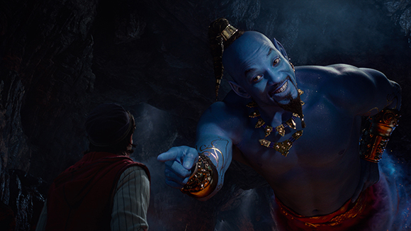 A large blue genie with a goatee points toward a young man in a dark cave.
