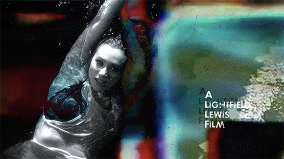 A black and white portrait of a woman underwater, overlaid with colorful, blurry light leaks and text.