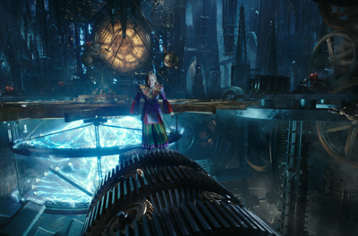 A person in a colorful costume stands on a glowing blue circular platform amidst giant gears and dark towers.