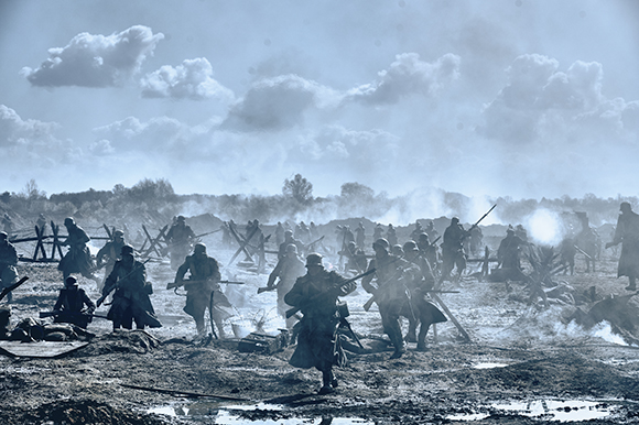 Soldiers in uniform move through a muddy, smoke-filled battlefield with wooden barricades in the background.