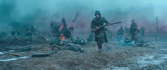 Soldiers in heavy coats run through a muddy, smoke-filled battlefield with explosions in the background.