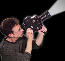 Man with glasses holds a vintage film camera, looking through the viewfinder as a bright light beam projects from the lens ag