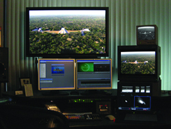 Multiple computer monitors on a desk showing aerial views of a landscape and various data interfaces.