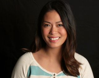 A smiling woman with long dark hair wearing a white and light blue striped shirt.