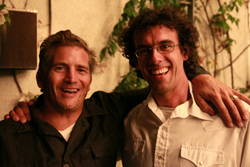 Two men smiling broadly while posing with their arms around one another's shoulders.