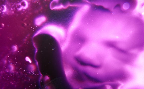 A blurry, close-up view of a face illuminated in bright purple and pink light.