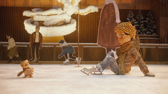 A paper cutout character sits on an ice rink next to a small owl.