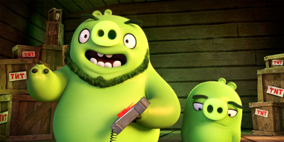 Two green animated pigs stand in a wooden room filled with TNT crates.