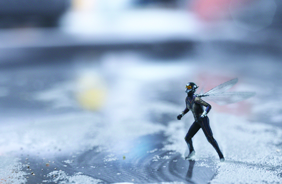 A small dragonfly figurine with translucent wings standing on a light-colored, textured surface.