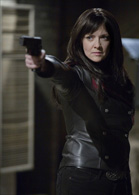 A woman with dark hair wearing a black leather jacket aims a handgun forward.