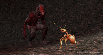 A person in a black tactical suit and mask crouches to look at a large, orange ant on a dark ground.
