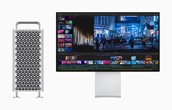 A silver computer tower stands next to a large widescreen monitor showing a video editing interface.