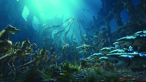 Underwater view of large stone statues and various sea creatures under bright light rays.