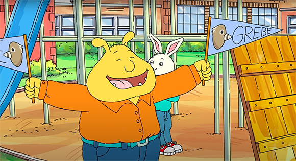 Animated yellow ant in an orange shirt and a white rabbit holding blue flags in a playground.