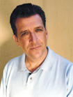A man with dark hair wearing a light blue polo shirt looking toward the camera.